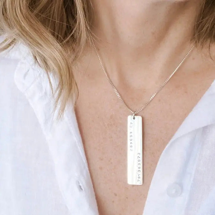 Woman wearing a sterling silver necklace with a rectangular pendant that show GPS Coordinates by CITRUS.