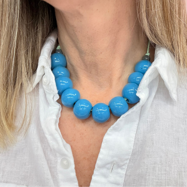 Blue beaded necklace worn by a person with a white shirt