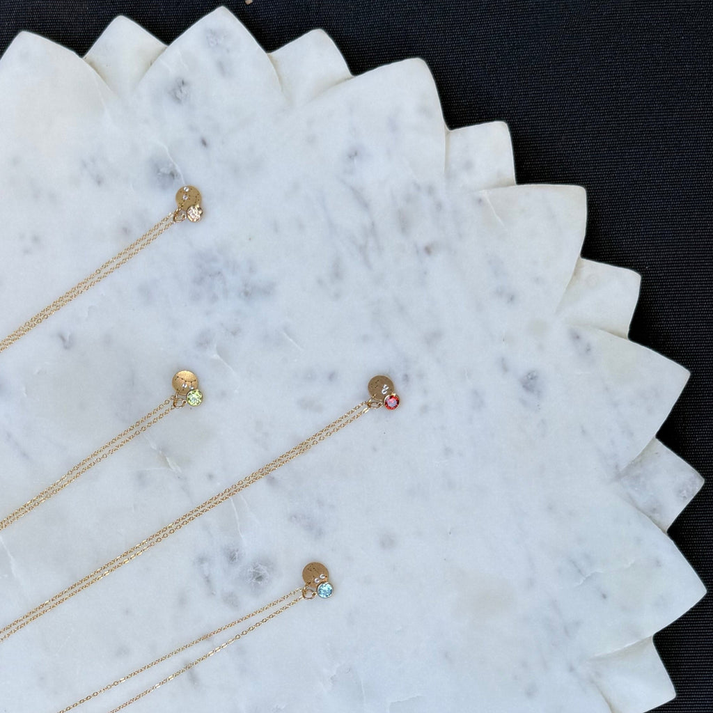 Gold necklaces with small gemstones on a marble surface