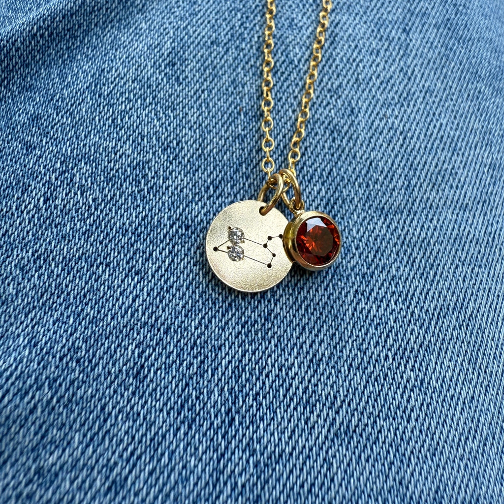 Necklace with a round pendant and red gemstone on a blue denim background