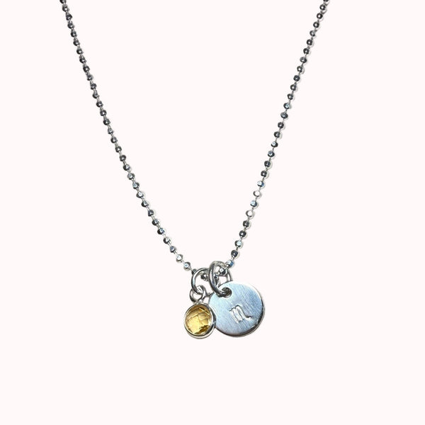 Necklace with two pendants on a beige surface 