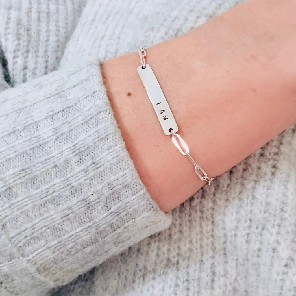 Silver bracelet with engraved name on a woman's arm.