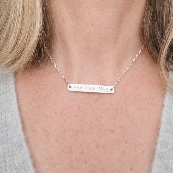 Silver bar necklace with engraved text on a person's neck