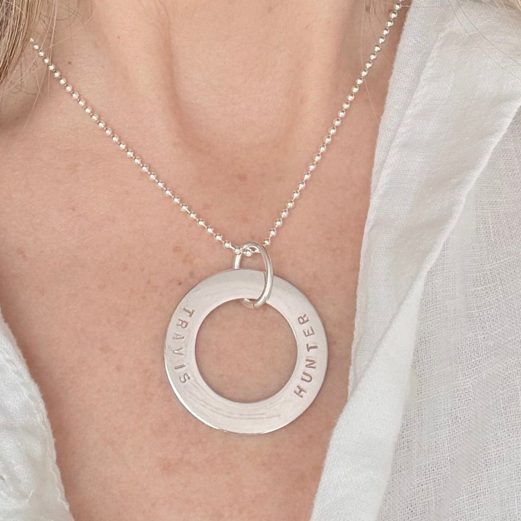 Mother wearing a silver personalized name necklace with a circular pendant
