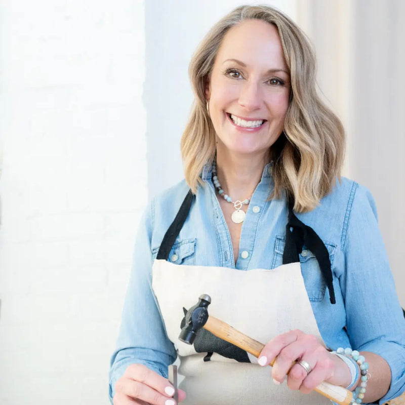 Owner of CITRUS at her jewelry bench hand-stamping a personalized pendant