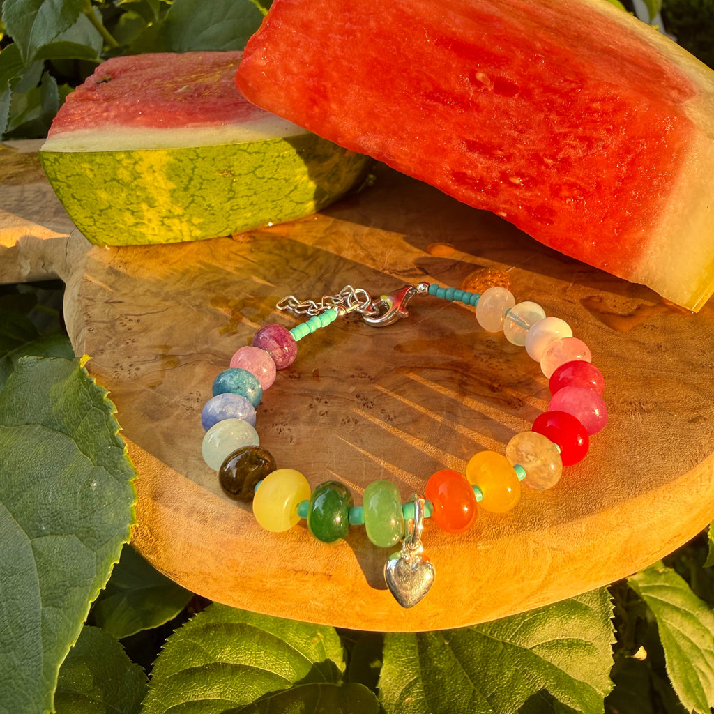 Colorful beaded bracelet on a wooden surface with green leaves in the background