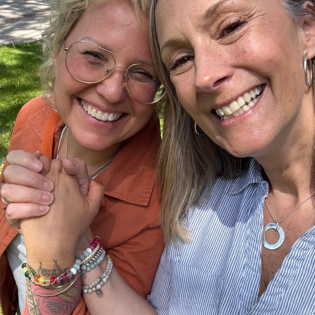 Two people smiling wearing the LOVE Bracelet